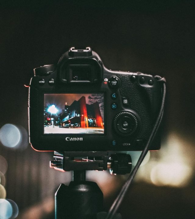 Close-up of a camera capturing a vibrant urban scene at night with a blurred bokeh background.